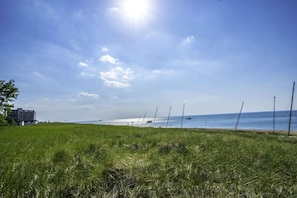 A grassy field with a clear sky and a distant view of the sea. - Main Street Retreat | Mid-century charm steps from the lake and arts district (Michigan City)