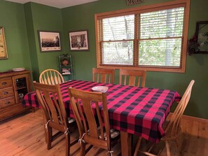 A dining area with a table set for four, wooden chairs, and a checkered tablecloth. - Mt. Baldy Cabin | Game Room, Fire Pit & The Dunes (Michigan City)