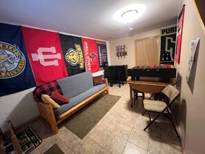 Een woonkamer met een bank, een eettafel en een vlag aan de muur.