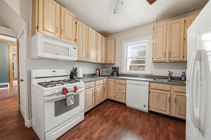A kitchen with wooden cabinets, a white stove, and a dishwasher. - Pine Street Flat | Steps to Everything (Michigan City)