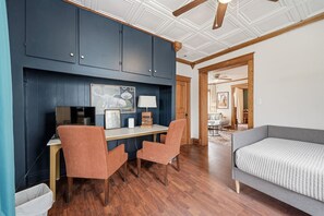 A room with a desk, two chairs, a bed, and a ceiling fan. - Pine Street Flat | Steps to Everything (Michigan City)