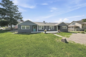 A two-story residential building with a front porch, a small deck, and a well-maintained lawn. - Prairie Retreat at Stop 1 (Michigan City)