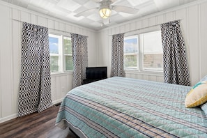 A bedroom with a bed, a television, and patterned curtains. - Prairie Retreat at Stop 1 (Michigan City)