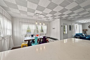 Ruokailutila, jossa on valkoisesta marmorista valmistettu pöytä, värikkäät tuolit ja ruutukuviollinen katto.