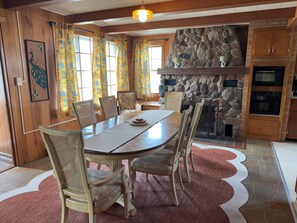 A dining area with a stone fireplace, wooden walls, and a dining table with chairs. - Retro on Wabash, Vintage Vibes, Modern Comfort (Michigan City)