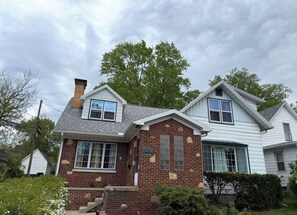 A two-story house with a brick facade, a chimney, and a number '1210' on the front. - Retro on Wabash, Vintage Vibes, Modern Comfort (Michigan City)