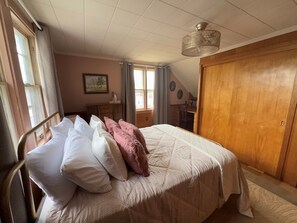 A bedroom with a bed, a wooden wardrobe, a desk with books, and a window. - Retro on Wabash, Vintage Vibes, Modern Comfort (Michigan City)