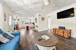 A spacious living room with a blue sofa, a wooden coffee table, and a TV mounted on the wall. - Sheridan Beach Bungalow (Michigan City)