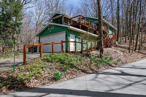 A two-story house with a garage, surrounded by trees and a garden. - The Tree House | Lake Views & Beach a Block Away (Sawyer)