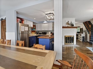 A modern kitchen with white cabinets, a stainless steel refrigerator, and a blue island. - Wasting Time at Stop 4 | Steps to Lake Michigan (Michigan City)