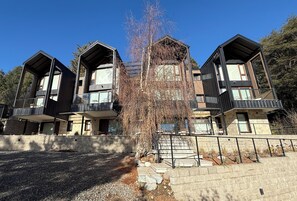 A modern multi-story residential building with a stone facade, balconies, and a gravel driveway. - Pine (San Carlos de Bariloche)
