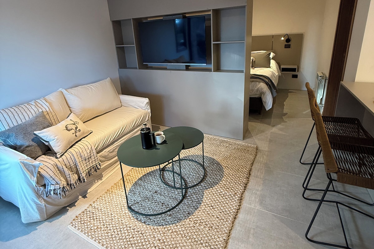 A modern living room with a sofa, coffee table, and a TV mounted on a wall.