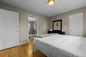 Une chambre à coucher comprenant un lit, une commode, un miroir et une porte donnant sur une salle de bain.