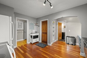 A modern kitchen with white cabinetry, a microwave, and a stainless steel trash bin. - Downtown Anoka 2BR Steps to Shops & Rum River (Anoka)