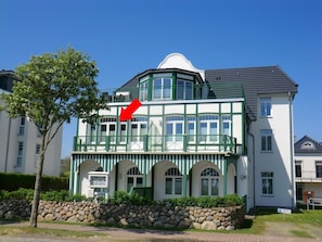 Ein zweistöckiges Gebäude mit einem Balkon, einer Steinmauer und blauem Himmel.