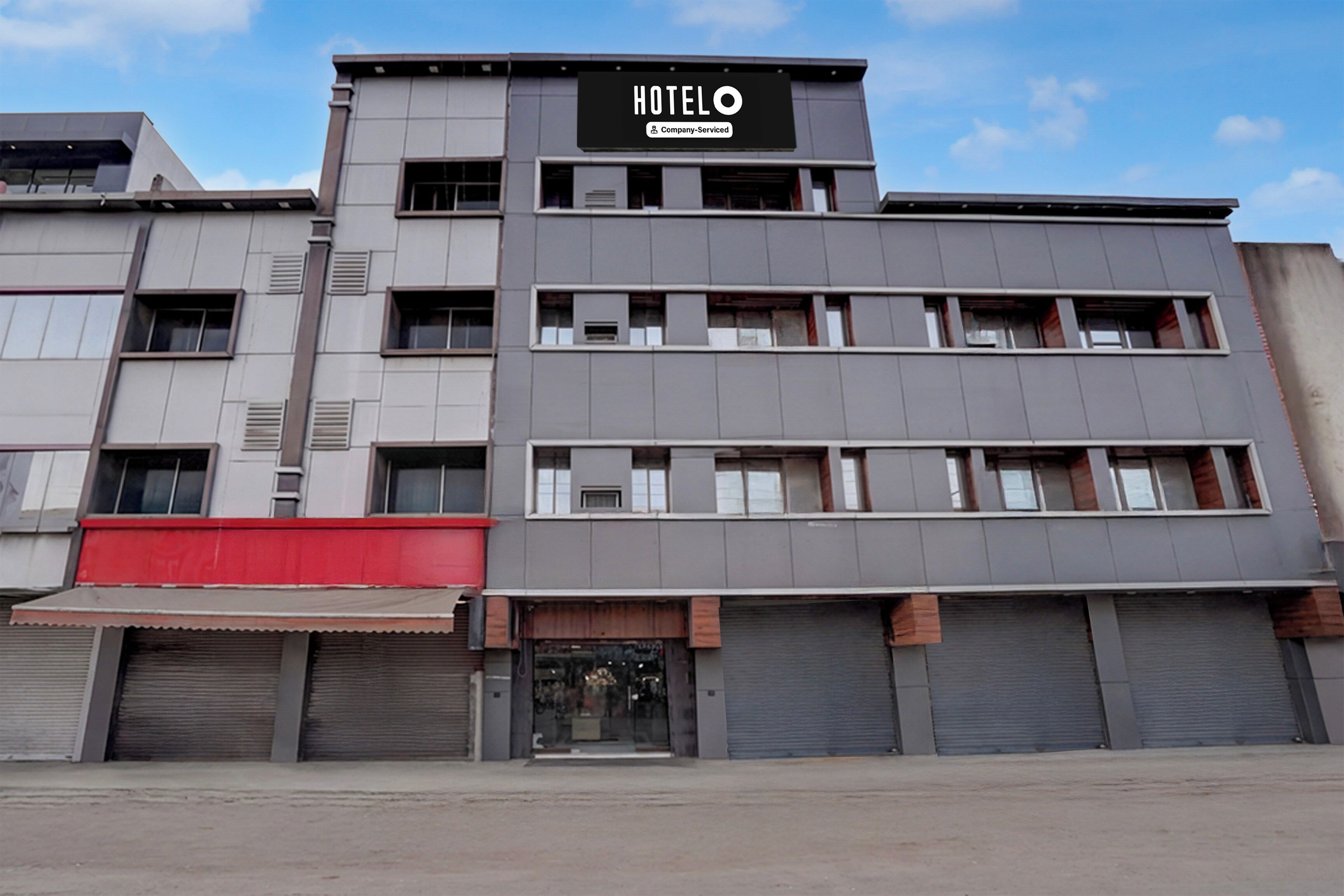 A modern hotel building with a sign that reads 'HOTEL' and 'Company-Serviced.'