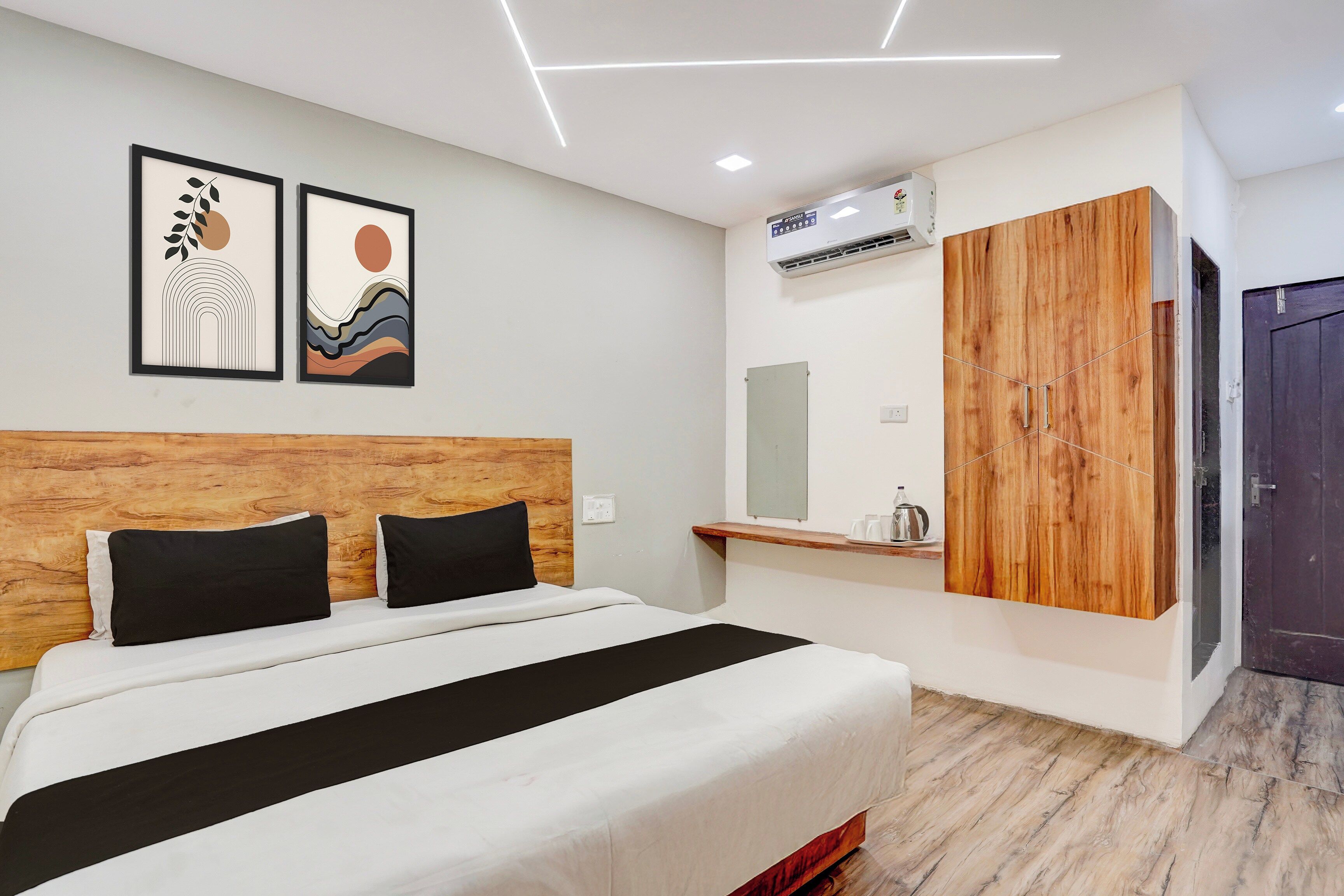 Una habitación de hotel moderna con una cama, cabecera de madera, armario y aire acondicionado de pared.