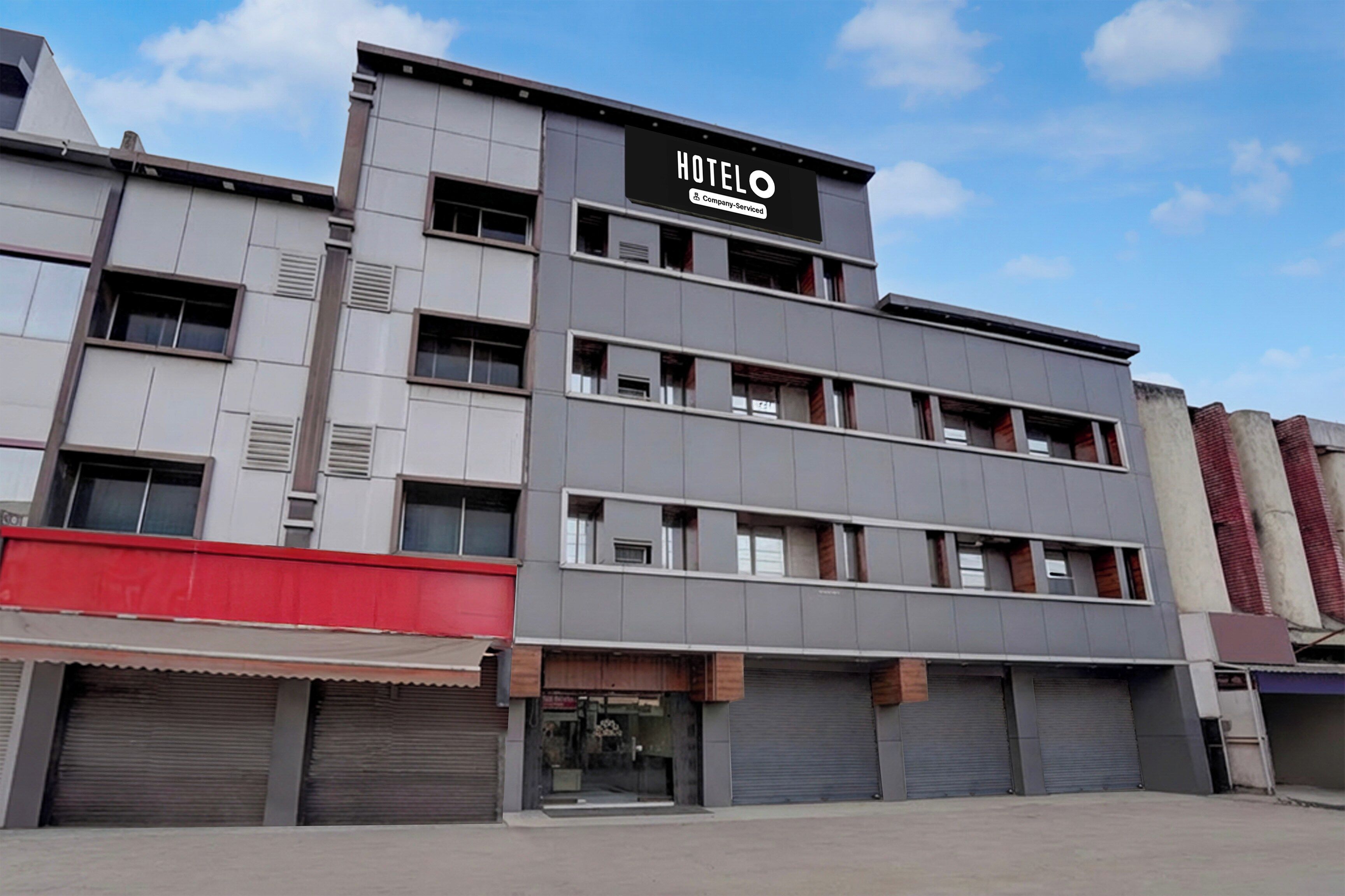 Un hotel de varios pisos con un llamativo letrero 'HOTEL' en la fachada, que presenta un estilo arquitectónico moderno con techo plano y grandes ventanales.