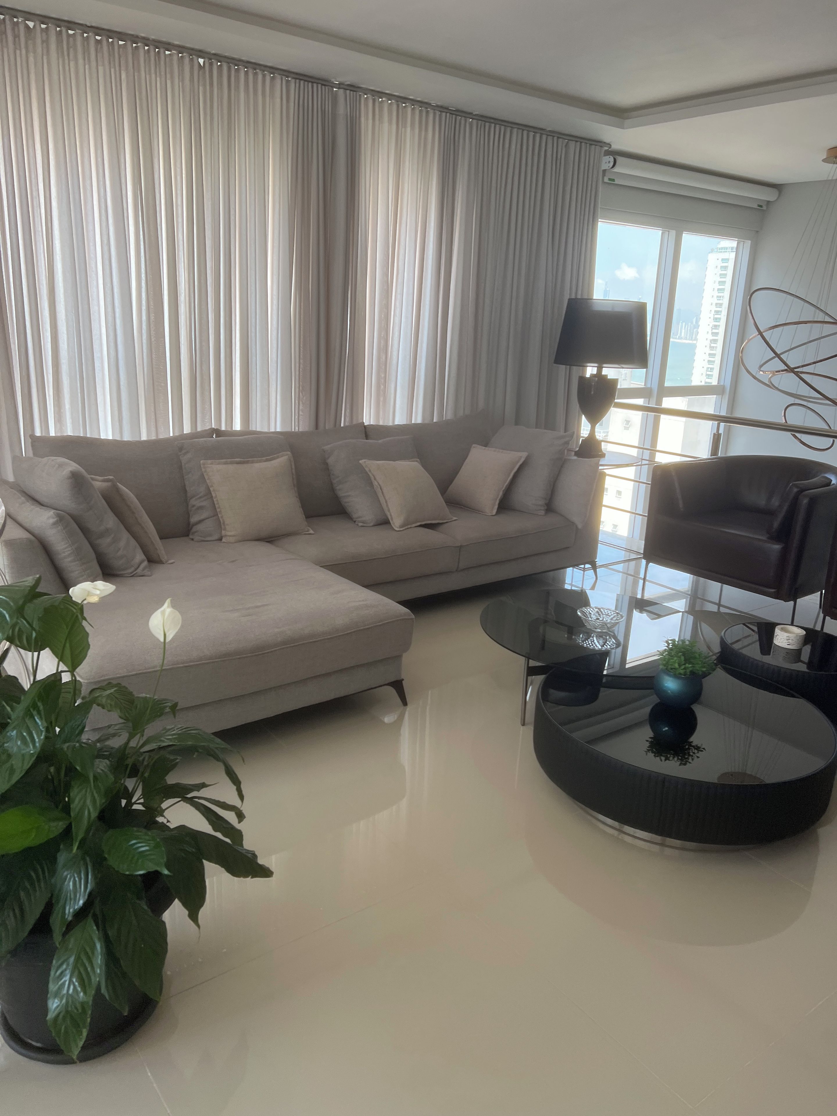 En moderne stue med en modulsofa, et glasbord og en potteplante.