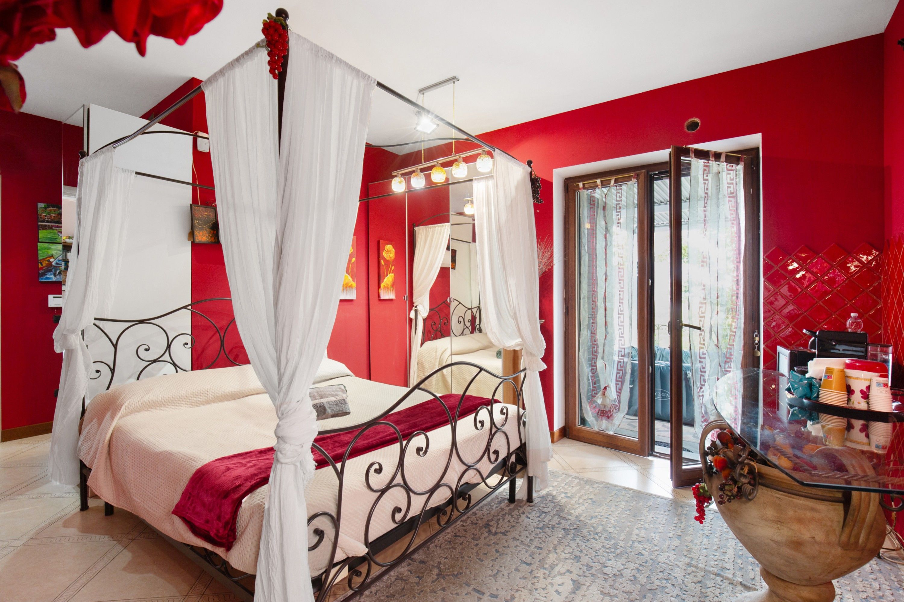 A four-poster bed with a canopy, a large mirror, and a glass door leading to a balcony.