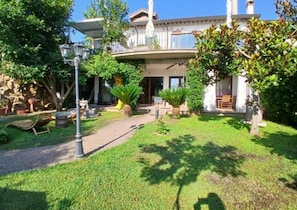A residential property with a well-maintained garden, outdoor seating, and a two-story building with a balcony.