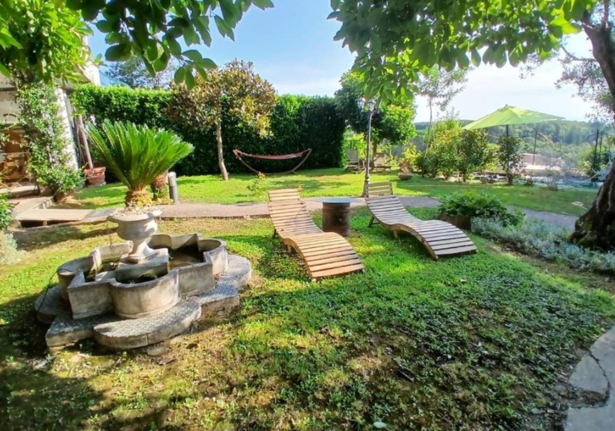 A garden with a wooden deck, a hammock, and a stone planter.