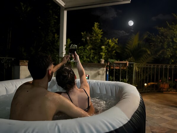 A couple in a hot tub with a moon in the background.