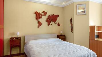 Una habitación de hotel con una cama grande, dos mesitas de noche, una obra de arte con un mapa mundial, un cuadro enmarcado y un armario de madera.