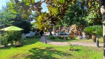Un jardín con un sendero, bancos y una pequeña fuente.
