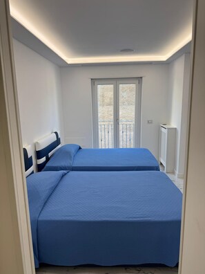 Ein Schlafzimmer mit zwei Betten, einem Fenster und einer Heizung.