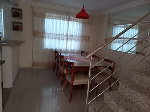 A dining area with a table and chairs, a staircase, and a red pendant light. - New Listing (Curitiba)