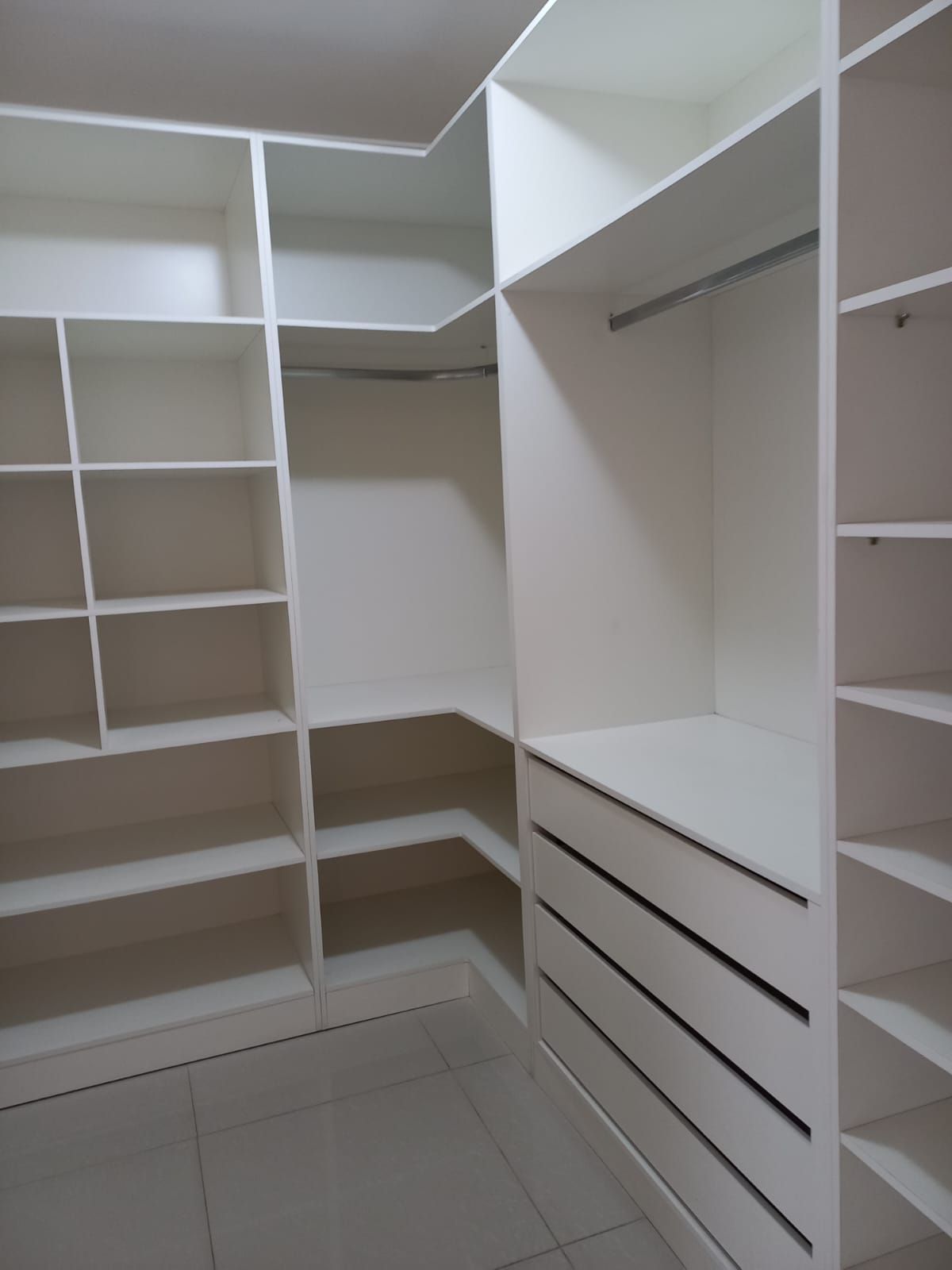 A walk-in closet with multiple shelves and drawers.