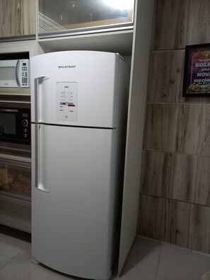 A white refrigerator with a digital control panel, a microwave above it, and a wooden wall panel. - New Listing (Curitiba)