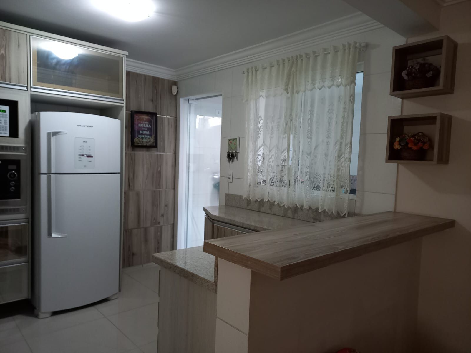 A kitchen with a built-in refrigerator, a microwave, and a wooden cabinet.