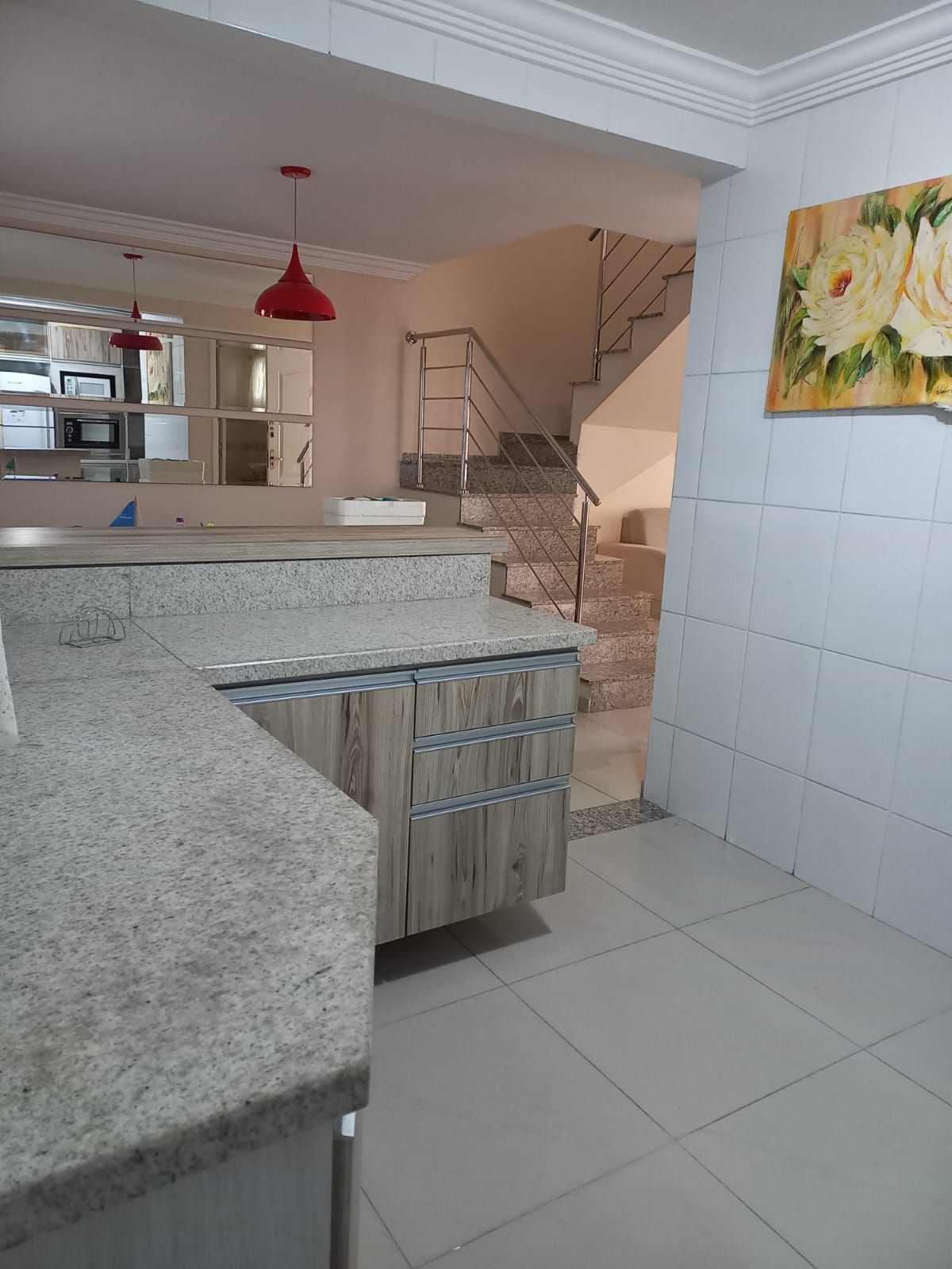 A modern kitchen with granite countertops, a wooden cabinet, and a red pendant light.