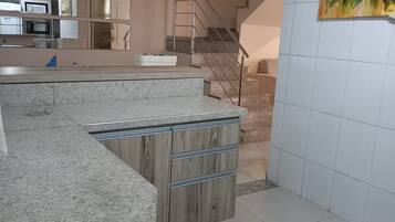A modern kitchen with granite countertops, a wooden cabinet, and a red pendant light.