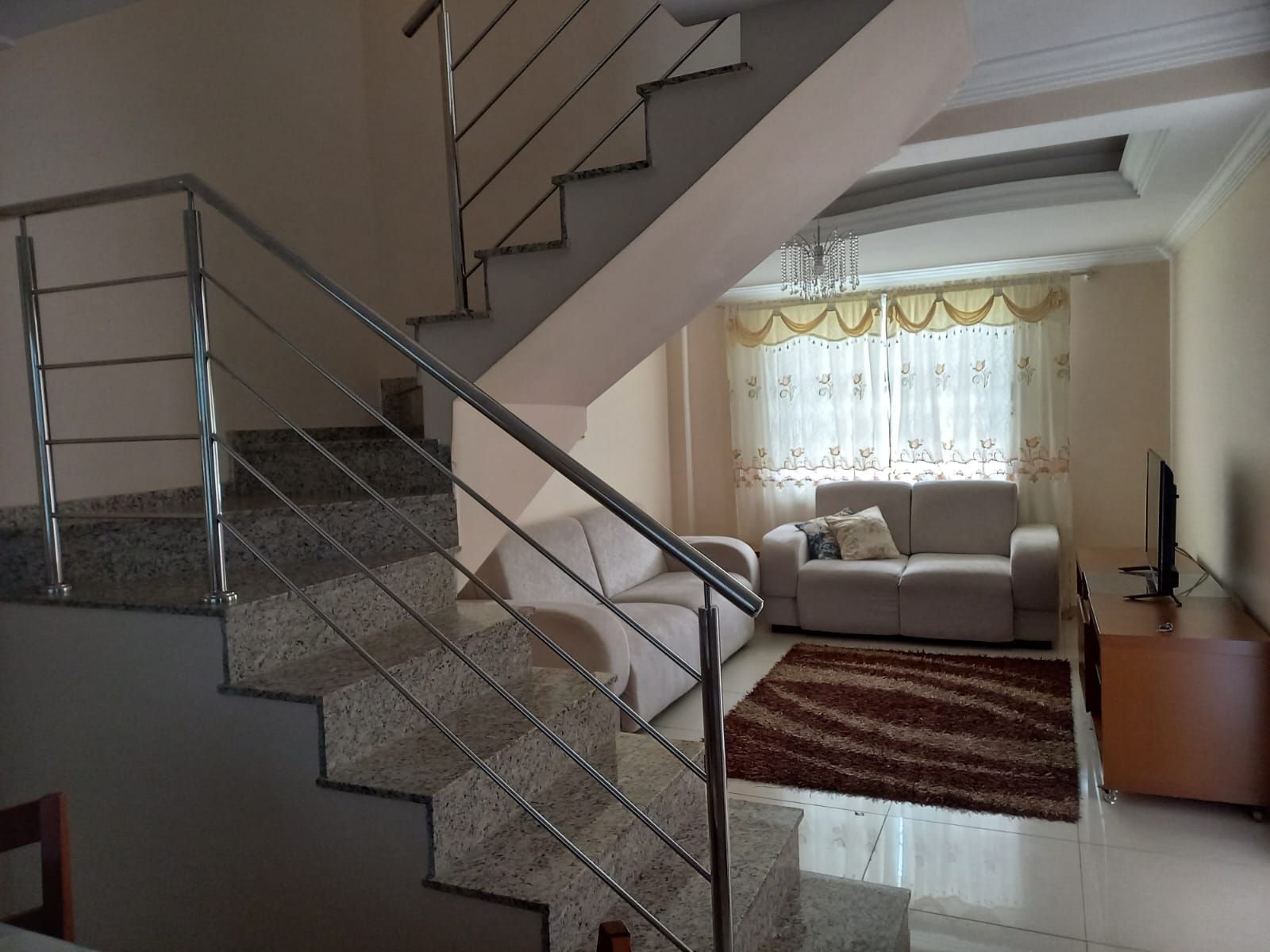 A staircase with metal railings leading to a living area with a sofa and a television.