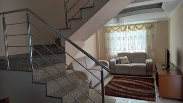 A staircase with metal railings leading to a living area with a sofa and a television.