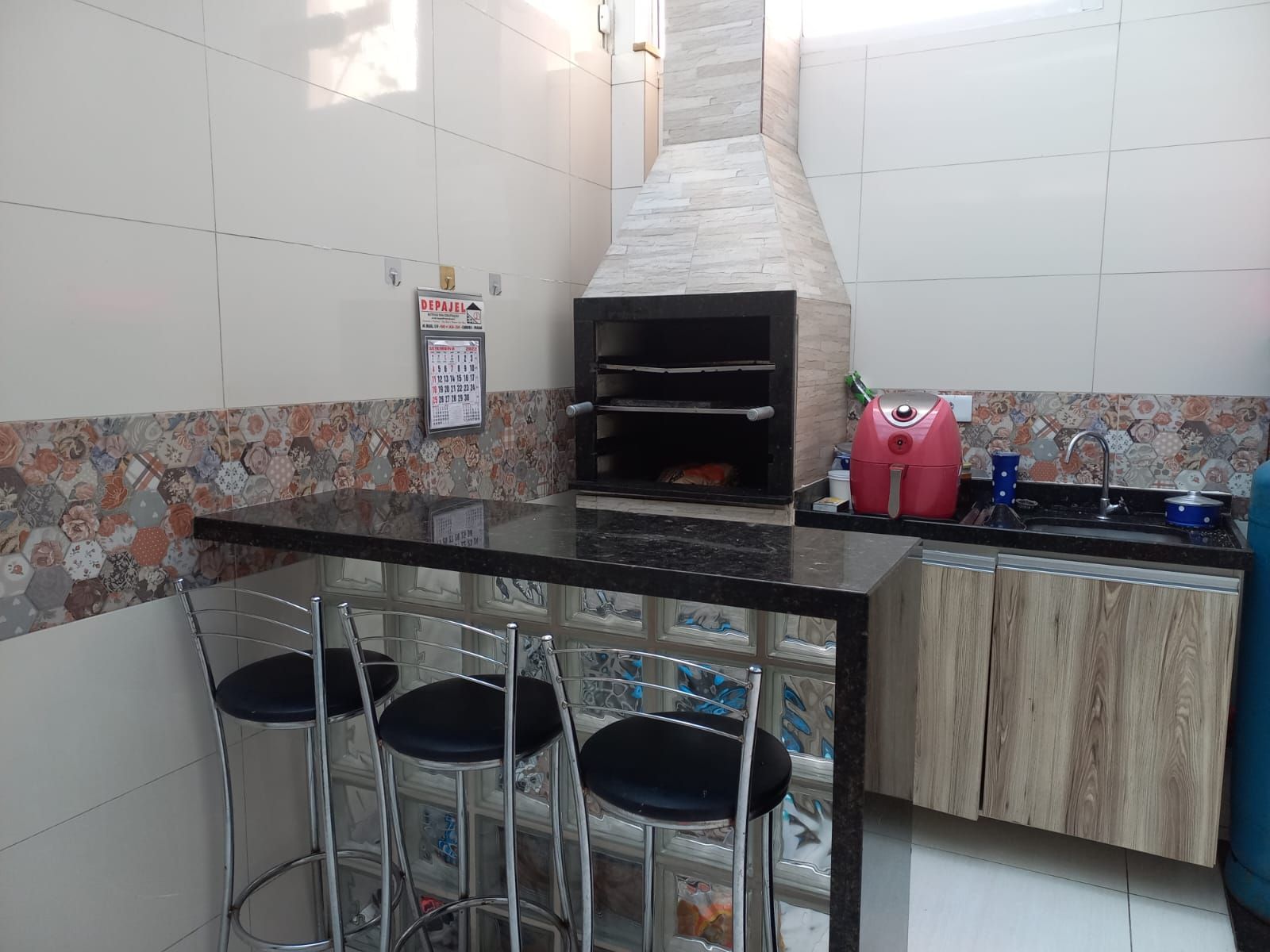 A kitchen with a built-in oven, a sink, and a bar stool area.