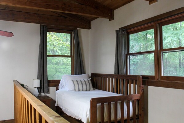 A single bed with a wooden headboard in a room with two windows, a lamp, and a view of trees. - Creekside - Pets ok/no hot tub (Purlear)