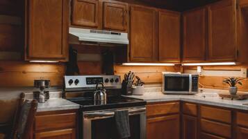 Une cuisine avec des meubles en bois, une cuisinière en acier inoxydable, un four à micro-ondes et une bouilloire.