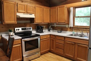 A kitchen with wooden cabinets, a stainless steel stove, a coffee maker, and a sink. - Creekside - Pets ok/no hot tub (Purlear)