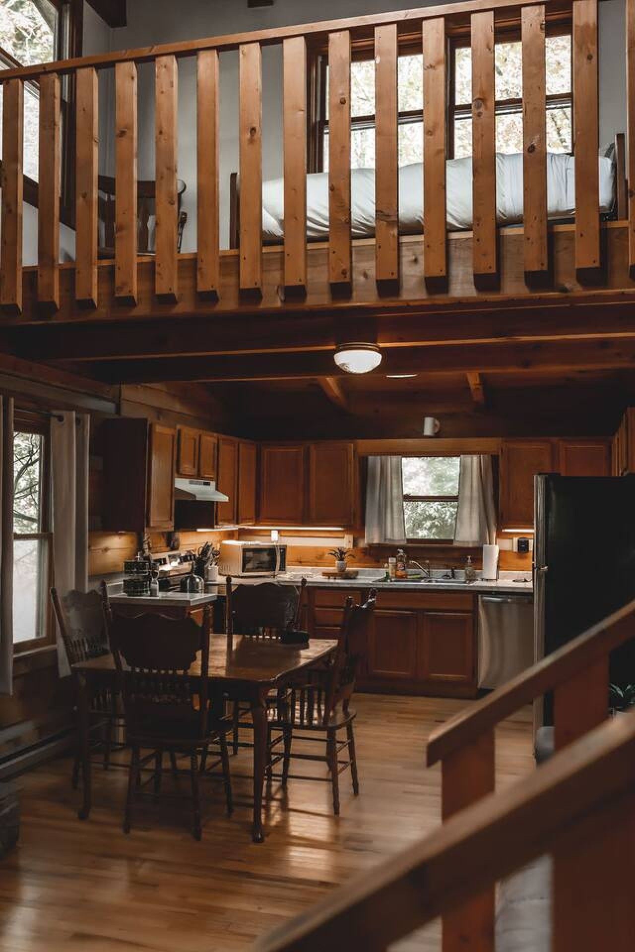 A wooden interior with a dining area, kitchen, and a loft space.
