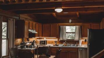 A wooden interior with a dining area, kitchen, and a loft space.