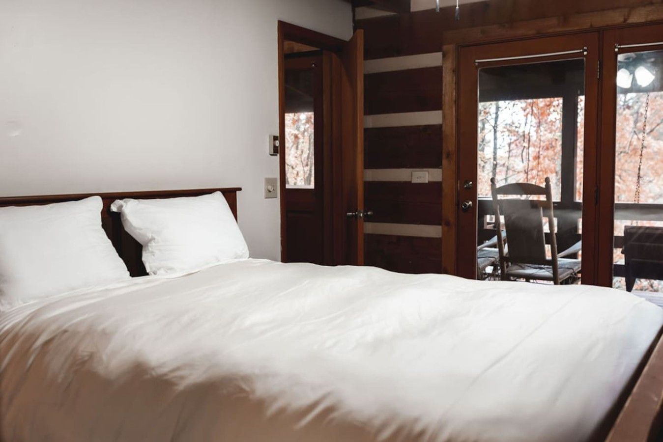 Un dormitorio con una cama grande, paredes de madera y vistas a una zona de estar al aire libre.