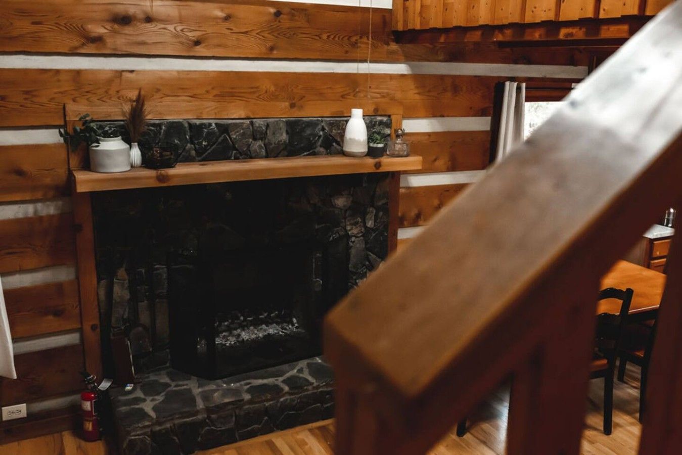A fireplace with a stone surround, wooden mantel, and decorative items.