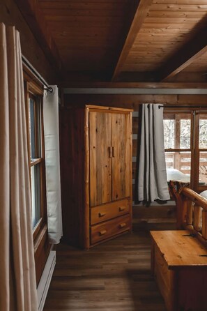 Een houten chalet interieur met een houten kast, een bank en een raam met gordijnen.