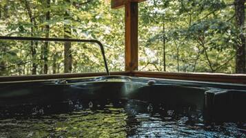 A hot tub with a wooden frame and a view of a forest through a window.