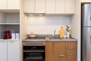Eine moderne Küche mit Backofen, Edelstahlkühlschrank und einer Arbeitsplatte mit Topf und Schneidebrett.