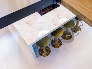 A kitchen with a marble countertop and four stools with metallic legs. - Heaven Lea Cottage (Oldham)